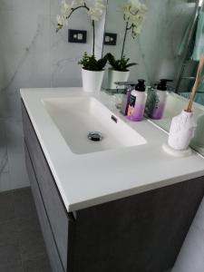 Un lavabo blanco en un baño con flores. en Three bedrooms two bathrooms ground floor only not the whole house, en Mount Maunganui