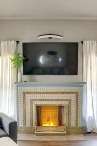 a living room with a fireplace with a tv above it at Charming 2 bed 1 bath Tudor - Near Plaza & Midtown in Oklahoma City