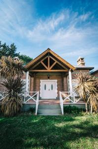 una casa de ladrillo con una puerta blanca y dos palmeras en Las Morenas en Sierra de la Ventana