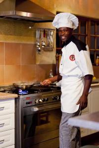 a chef standing in front of a stove in a kitchen at Needles Lodge in Marloth Park
