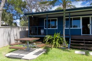 uma casa azul com uma mesa de piquenique no quintal em Silversands Beach House em Berrara