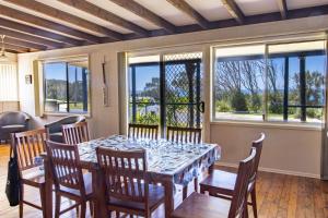 uma sala de jantar com mesa, cadeiras e janelas em Silversands Beach House em Berrara