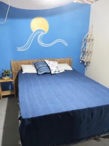 a blue bedroom with a bed with a painting on the wall at Casa Mar in Baía Formosa