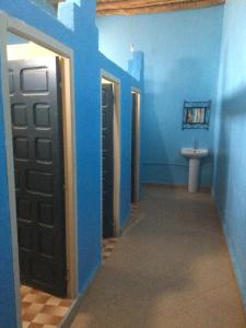 een badkamer met blauwe muren, een deur en een wastafel bij Habitation Dunes merzouga in Merzouga