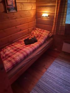 a bed in a wooden room with a bag on it at Macktunet - Retro log cabin from the 70s in Malangen 