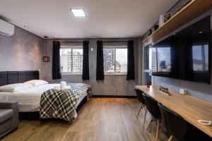 1 dormitorio con 1 cama, escritorio y ventanas en Sky155 - Studio c/ Vaga Próx. à Estação da Luz: Seu Refúgio Urbano!, en São Paulo