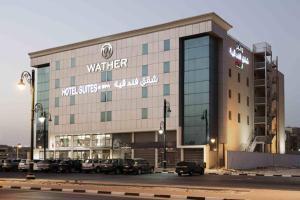 a building with cars parked in a parking lot at Watheer Hotel Suite in Dammam