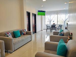 a living room with couches and a tv on the wall at Suite Familiar en Puerto Ayora in Puerto Ayora