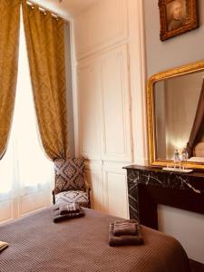 ein Schlafzimmer mit einem Bett mit einem Spiegel und einem Stuhl in der Unterkunft CLUB NAPOLEON SAUMUR in Saumur
