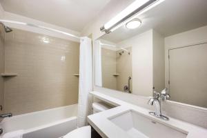 a bathroom with a sink and a tub and a mirror at Sonesta Simply Suites Parsippany Morris Plains in Morris Plains