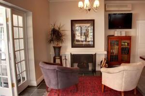 a living room with two chairs and a fireplace at Touch of Class Guest House in Pretoria