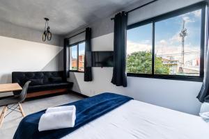 1 dormitorio con cama, sofá y ventanas en AA - Studio Encantador na Bela Vista, Próximo à Avenida Paulista, en São Paulo