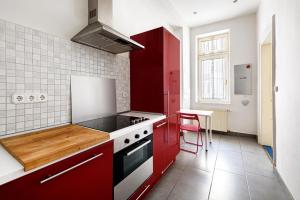 ブダペストにあるAlessia Apartment City Centerのキッチン(赤いキャビネット、コンロ付)