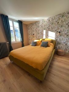 Un dormitorio con una cama grande con sábanas y almohadas amarillas. en Maison d'hôtes de la prison en toutes libertés, en Espalion