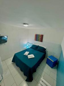 a bedroom with a blue bed with two towels on it at Casa da Lua Buzios in Búzios