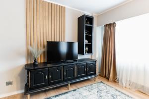 a living room with a television on a black dresser at Beautiful and cozy 2 bedroom apartment with living room loft in Cluj-Napoca