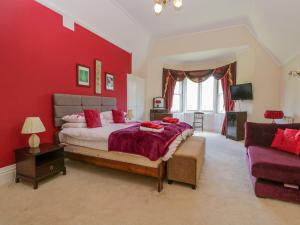 a red bedroom with a large bed and a couch at Millwood Manor in Barrow in Furness