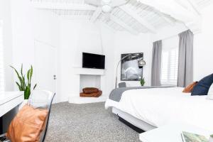 a white bedroom with a bed and a tv at Alcazar Palm Springs in Palm Springs