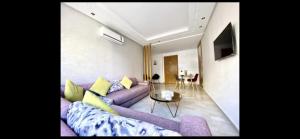 Bel appart+2 ROOM+WIFI+GARE CASA VOYAGEUR+TRAM في الدار البيضاء: غرفة معيشة مع أريكة أرجوانية وطاولة