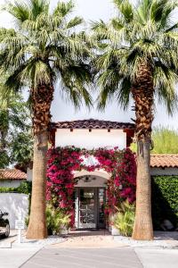 two palm trees in front of a building with flowers at Alcazar Palm Springs in Palm Springs