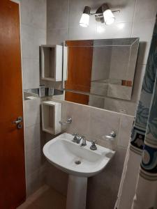 y baño con lavabo blanco y espejo. en Departamento centro Santiago del Estero en Santiago del Estero