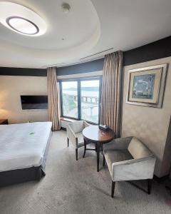 ソウルにあるNiagara Hotelのベッド、テーブル、椅子が備わるホテルルームです。