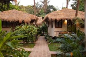 a pathway leading to a house with thatched roofs at Anahata Retreat Sea Front Resort Ashvem in Mandrem