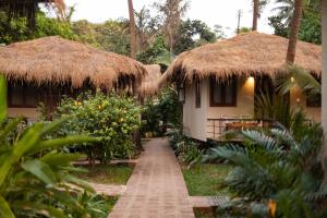 a pathway leading to a house with thatched roofs at Anahata Retreat Beach Front Resort in Mandrem +152 photos