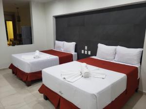 Cette chambre comprend 2 lits avec des draps rouges et blancs. dans l'établissement MALAKI, à Los Ayala