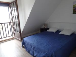 a bedroom with a blue bed and a large window at Nice duplex apartment, 400 m from the beach in Courseulles-sur-Mer