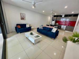 a living room with two blue couches and a table at Magnum Serviced Apartments in Darwin