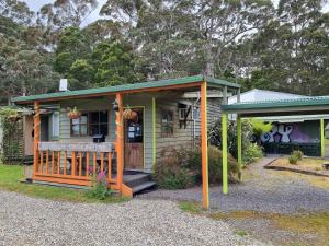 a small green and yellow house with a porch at Strahan Backpackers in Strahan