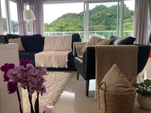sala de estar con sofá azul y flores púrpuras en Cobertura Duplex - La Belle Vue - Canajurê, en Florianópolis