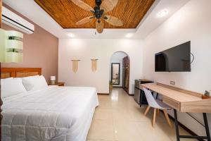 Schlafzimmer mit einem Bett, einem Schreibtisch und einem Deckenventilator in der Unterkunft Hotel Arco Iris in Tamarindo
