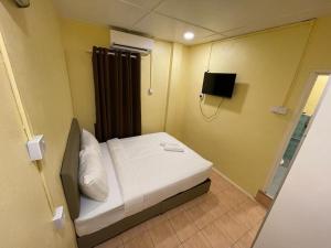 a small bed in a small room with a television at Hotel Sri Maju Jaya in Kota Bharu