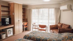 a hotel room with a bed and a couch and a table at Downtown Motel Warrnambool in Warrnambool