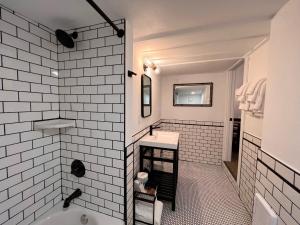 Baño blanco con bañera y lavamanos en The Seaview Cottages en Seaview