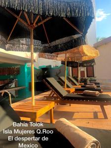 a room with a bunch of chairs and an umbrella at Bahia Tolok in Isla Mujeres
