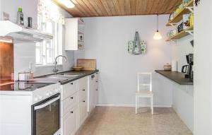 Una cocina con gabinetes blancos y un fregadero. en Cozy Home In Nexø With Wifi, en Neksø