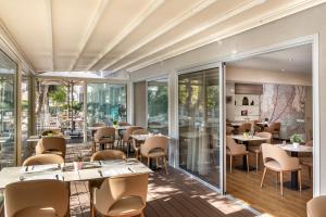 a restaurant with tables and chairs and windows at Almond Business Hotel in Nicosia