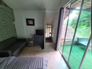 a room with a couch and a tv and a window at Phuphavaree by Tahug Sai Yok in Ban Ai Hit