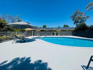 a swimming pool with an umbrella and a table and chairs at Nagambie Motor Inn and Conference Centre in Nagambie