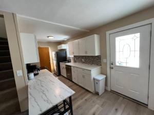 a kitchen with white cabinets and a white door at Snug, neighborly home perfect for your small group in Billings