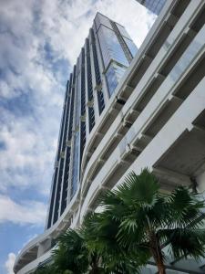a tall building with a palm tree in front of it at Alexa Meisterstadt pollux habibie in Batam Center
