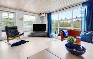 sala de estar con TV y algunas sillas y ventanas. en Cozy Home In Blvand With Wifi en Blåvand