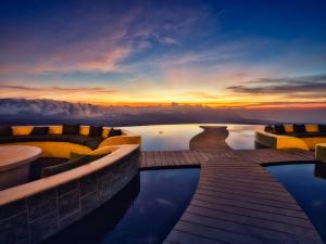 a hotel pool with a sunset in the background at Elevate Bali in Munduk