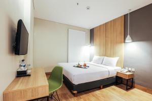 Dormitorio con cama, escritorio y TV en Hotel Citradream Semarang, en Semarang