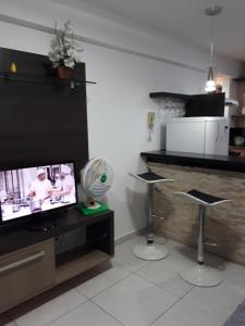 sala de estar con TV, 2 taburetes y ventilador en Apartamento Atlantico Tambaú, en João Pessoa