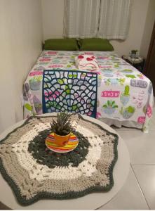 a bedroom with a bed and a table with a blanket at Praia do Rosa loft com cozinha in Imbituba