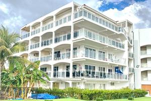 un gran edificio blanco con un hombre de pie en un balcón en Lux Maho Reef 1BR Suite Condo next to The Morgan Resort, en Maho Reef